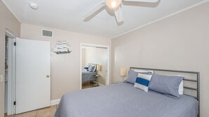 Un dormitorio con cama, ventilador de techo, puerta y espejo.