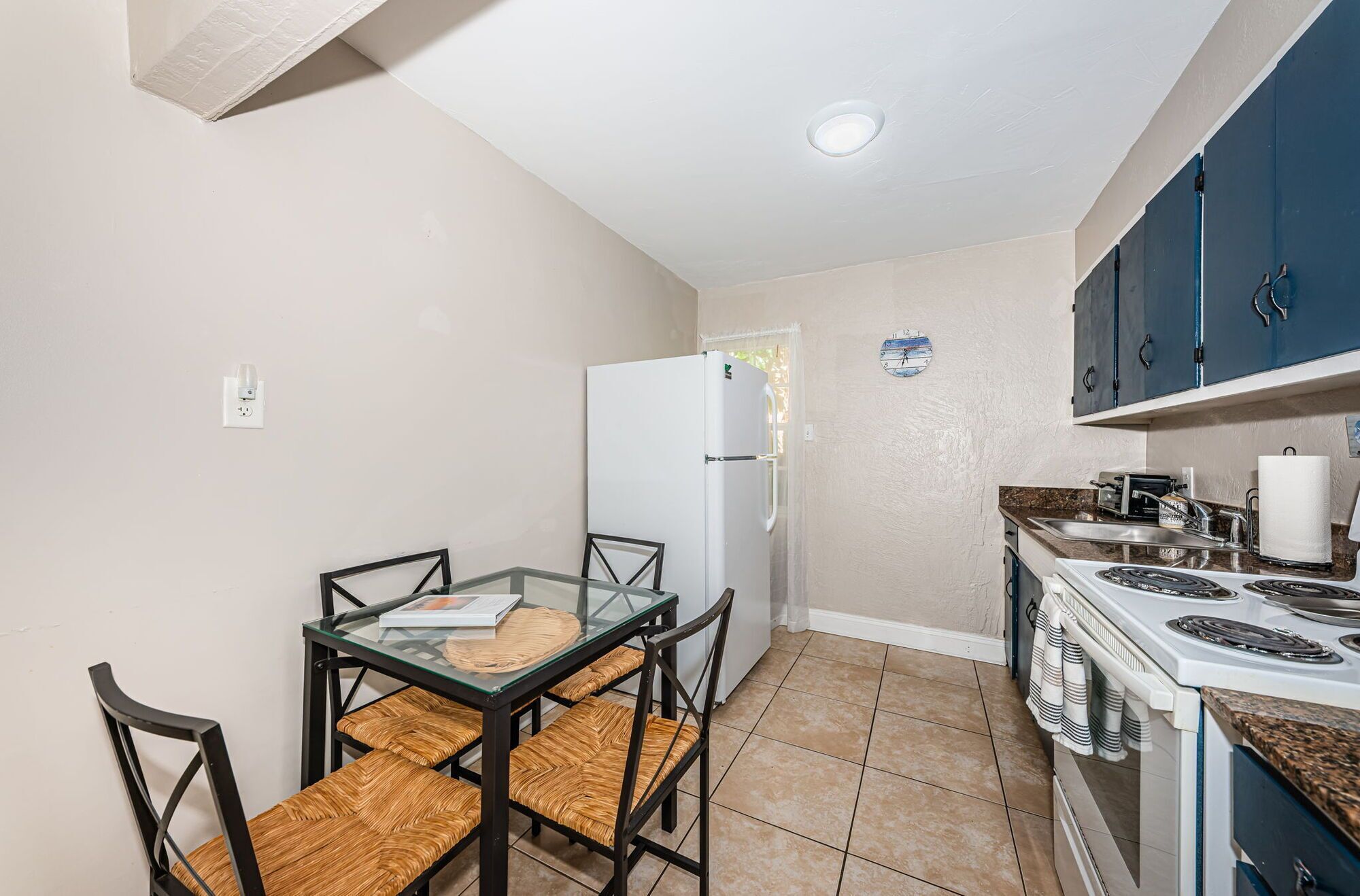 A compact kitchen with a refrigerator, stove, and dining table with chairs.