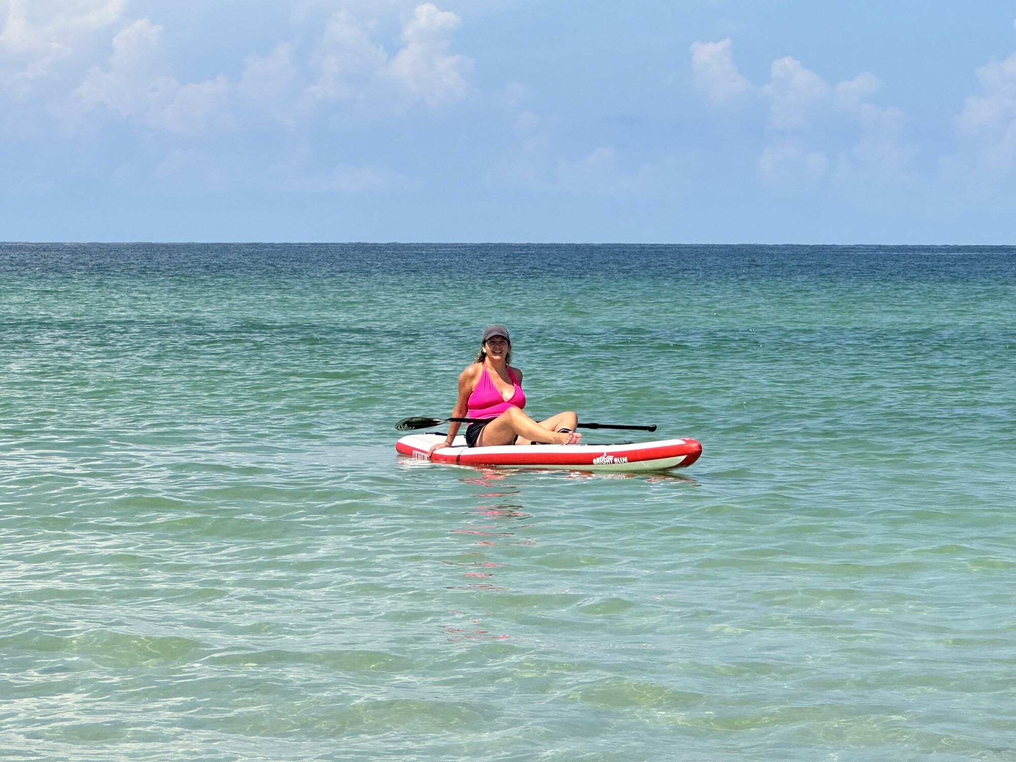 A person sitting on a paddleboard in the ocean.