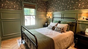 Un dormitorio con cama, ventilador de techo, ventana y pared con diseño.