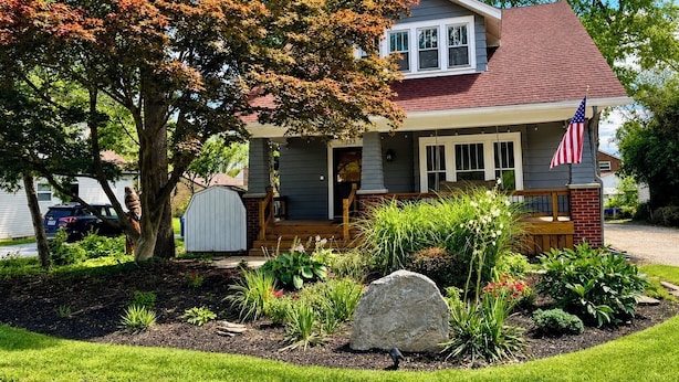 A two-story house with a front porch, a mailbox, and a large rock in the front yard. - "The Owl's Nest" Updated Craftsman home overlooking Old Town Park. (Westerville)