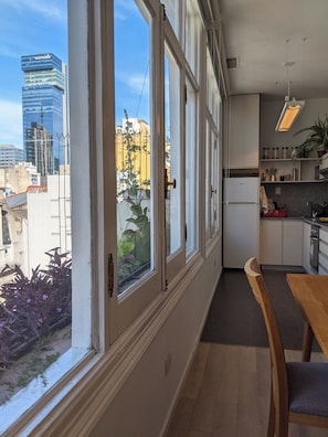 A modern kitchen with large windows, a dining area, and a view of the cityscape. - Stylish apartment in downtown, 200m from Obelisco! (San Nicolas)