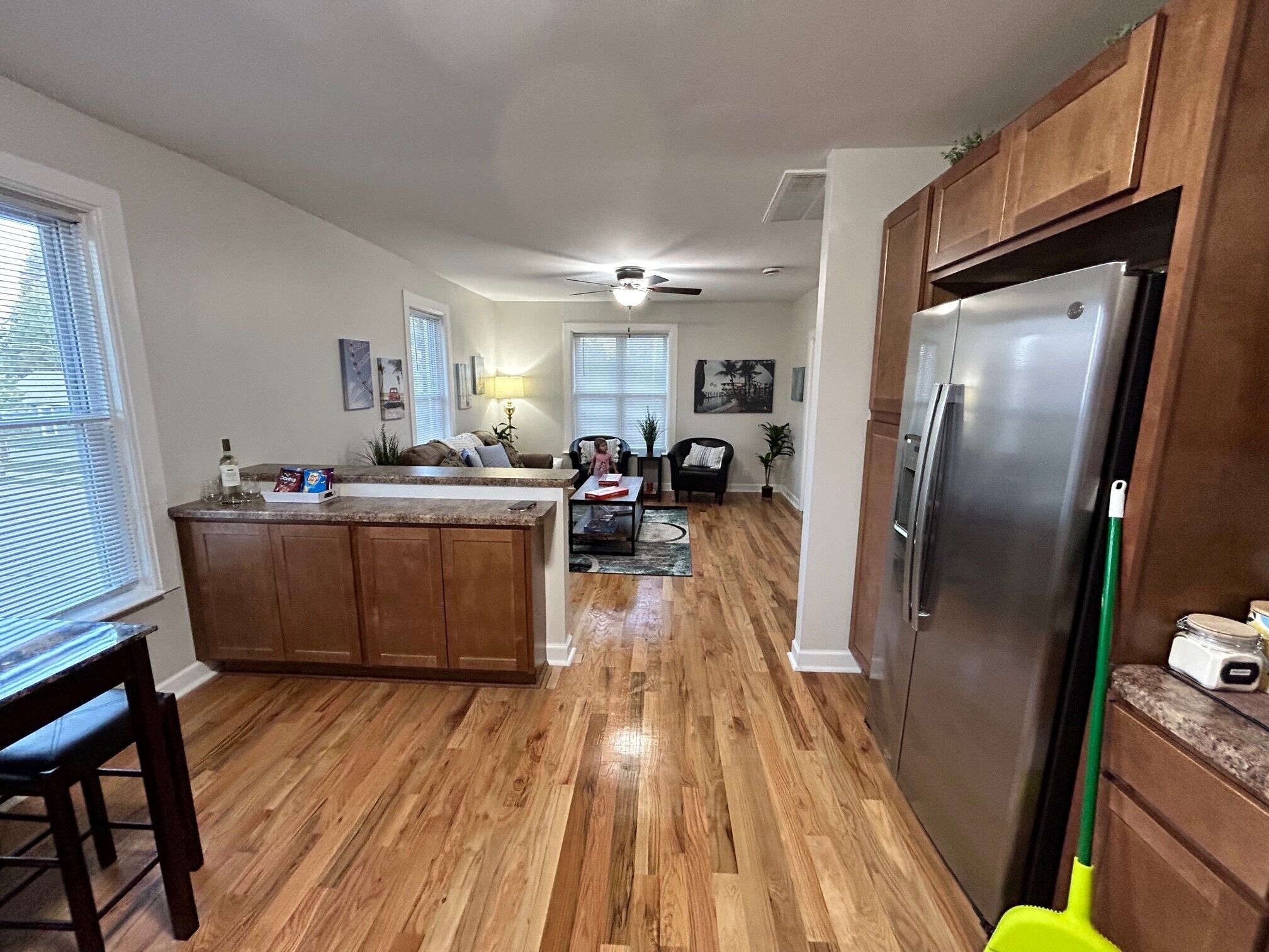 A spacious kitchen with wooden flooring, a central island, and a large refrigerator.