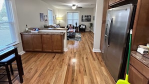 A spacious kitchen with wooden flooring, a central island, and a large refrigerator. - Beachcomber! Pro Cleaned, Self Check in Sleeps 7 (Racine)