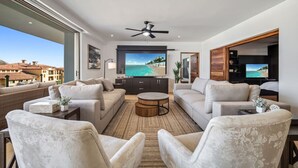 Un salon moderne doté d’un grand téléviseur, de sièges confortables et offrant une vue sur l’océan.