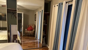 A hotel room with a wooden floor, a bed, a chair, and a wardrobe.
