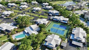 An aerial view of a residential area with multiple houses, a tennis court, and a swimming pool.
