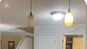 A kitchen with granite countertops, a wooden cutting board, and hanging pendant lights.