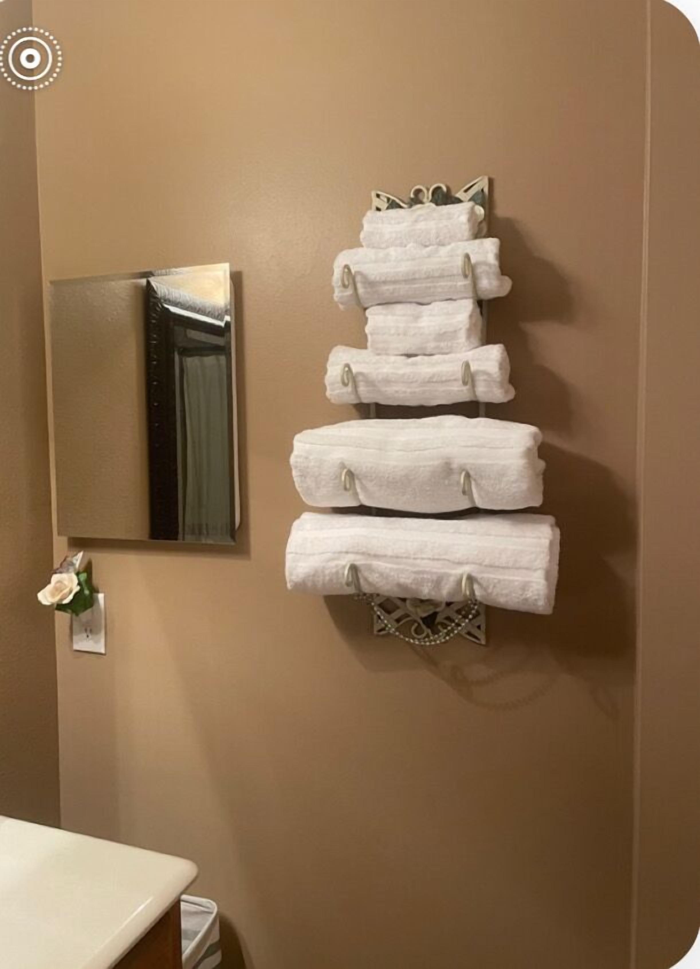 Une salle de bain avec un miroir, un porte-serviettes avec plusieurs serviettes et des toilettes.