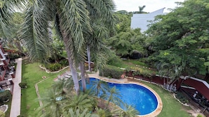 Zona residencial con piscina rodeada de palmeras y un césped bien cuidado.
