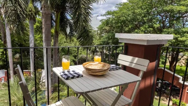 Un balcón con una mesa lista para el desayuno, que incluye un tazón y un vaso de jugo de naranja.