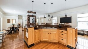 A spacious kitchen with wooden cabinets, a central island, and pendant lighting. - BigBear Lodge: Mt. Sunapee / Hot tub / Firepit (New London)