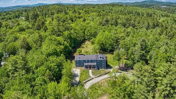 A large, two-story house surrounded by dense forest, with a clear sky above. - BigBear Lodge: Mt. Sunapee / Hot tub / Firepit (New London)