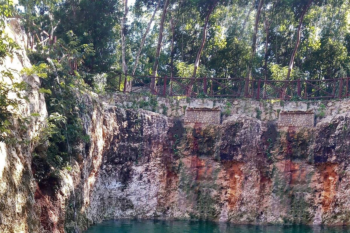Una piscina natural rodeada de acantilados rocosos y abundante vegetación.