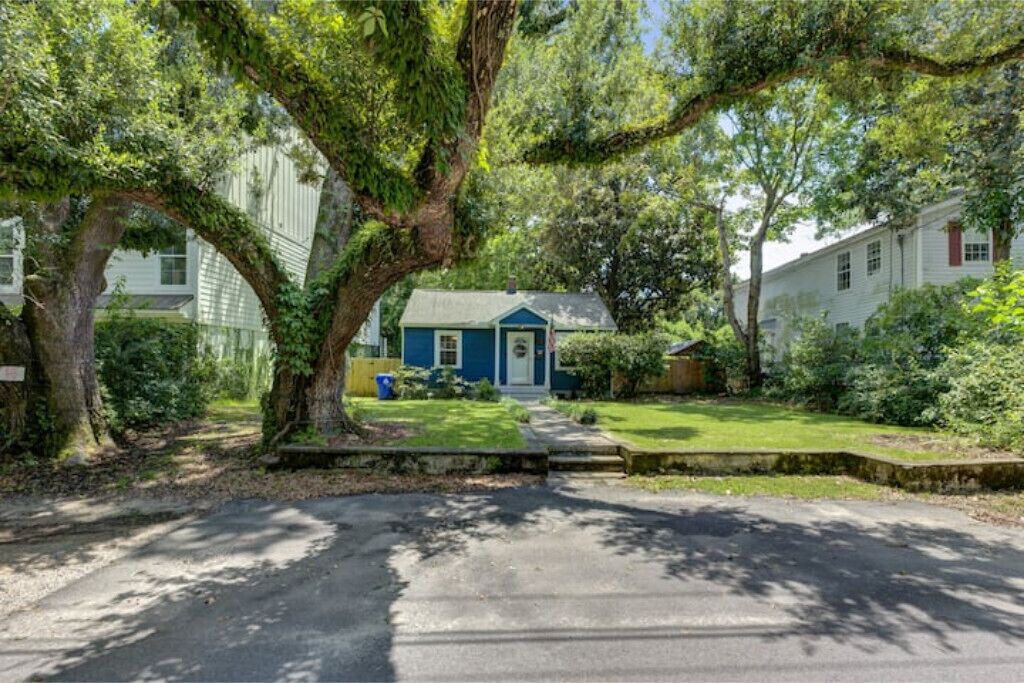 En boligejendom med et blåt hus, en forhave og en indkørsel til huset.