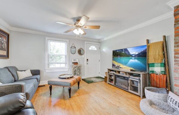 A living room with a sofa, a coffee table, a TV, and a fireplace.