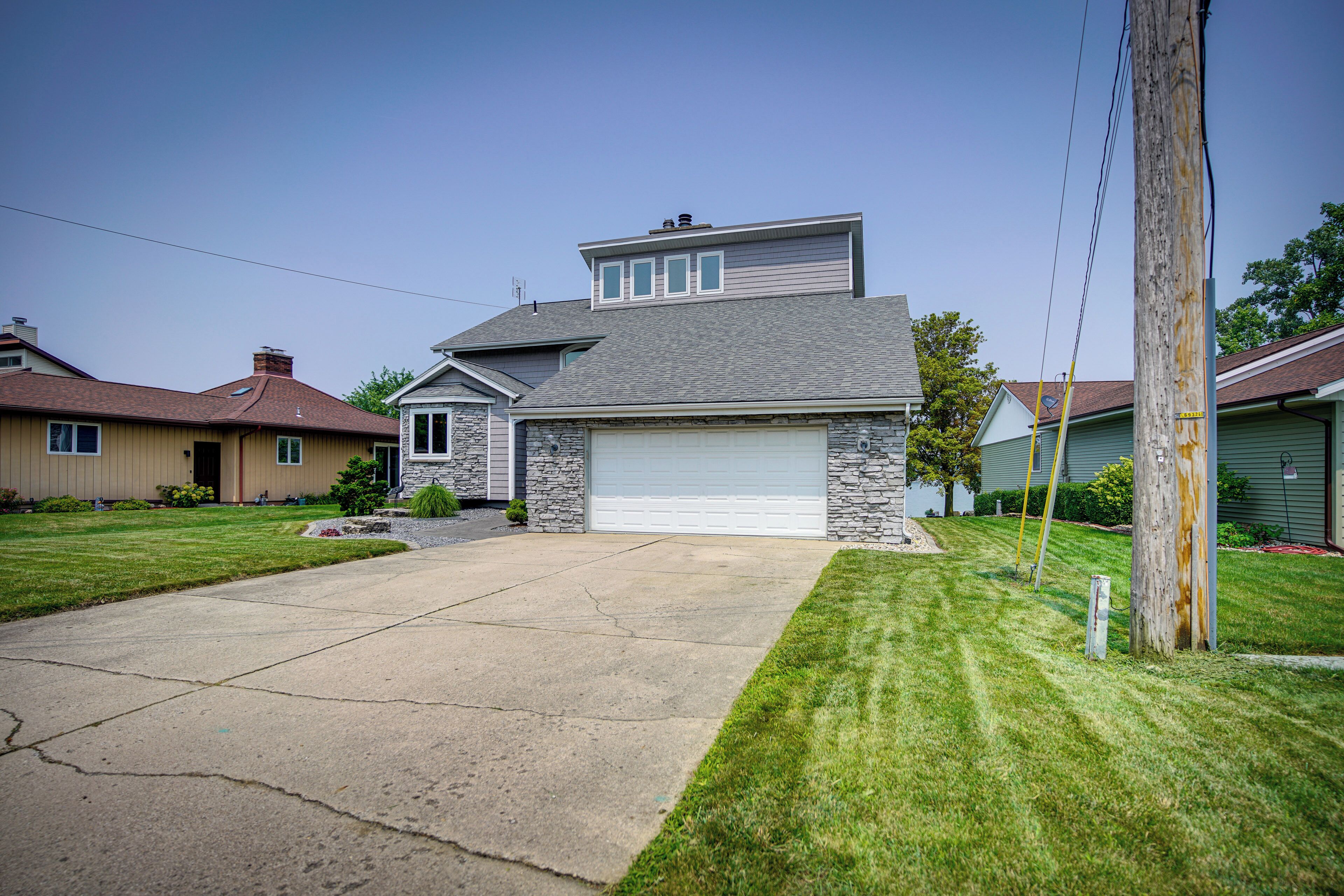 A two-story house with a stone facade, a garage, and a well-maintained lawn.