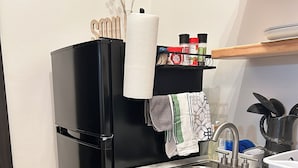 Una cocina moderna con un refrigerador negro, un lavamanos de acero inoxidable y una encimera de mármol.