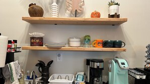 A kitchen with a sink, coffee maker, and shelves with dishes and a pumpkin. - Brand new, modern, private, and cozy 430 sq. ft apartment across from city park! (Mobridge)