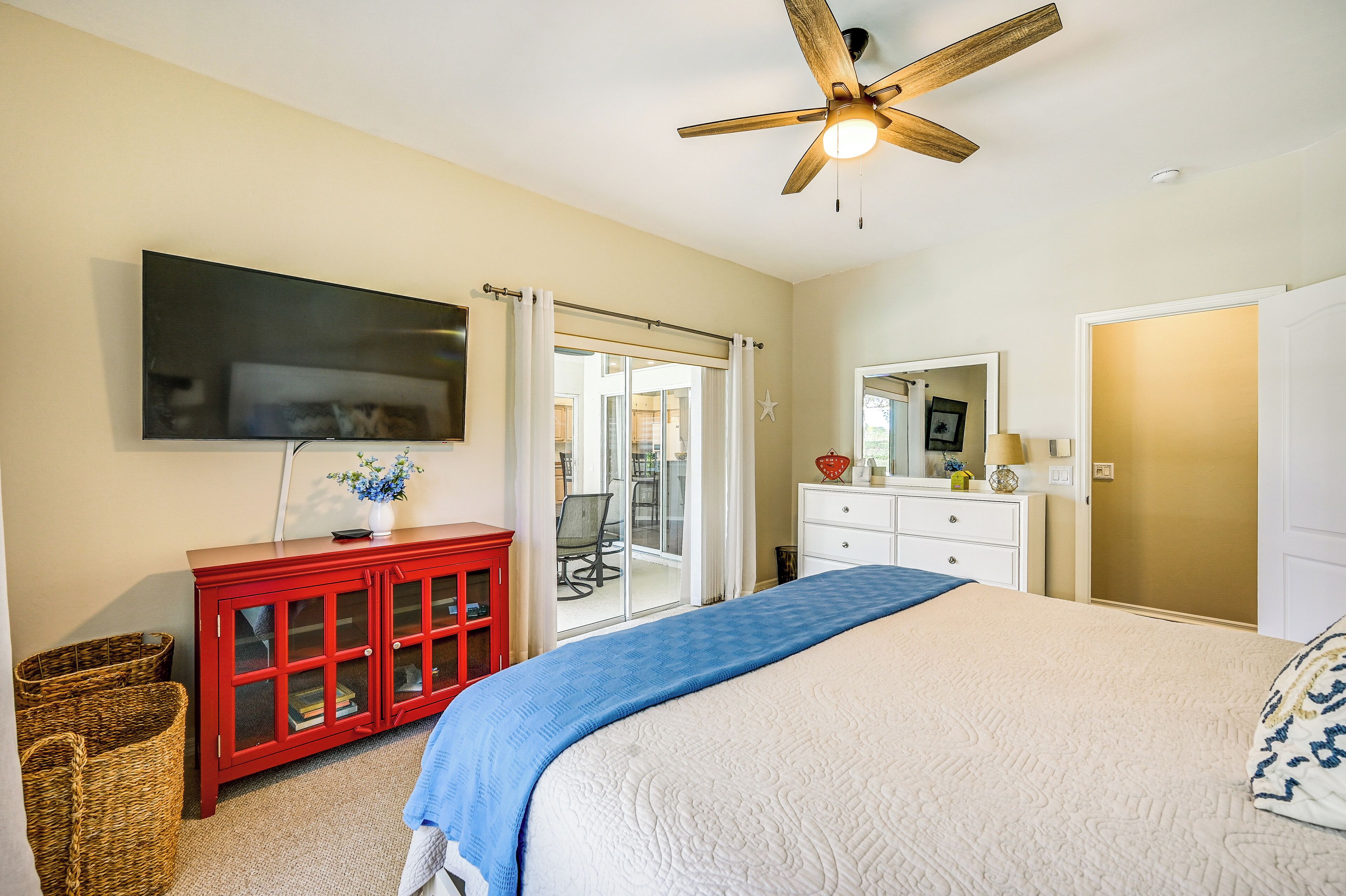 Une chambre à coucher avec un lit, une armoire rouge, un téléviseur et un ventilateur de plafond.
