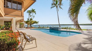 A modern house with a pool, palm trees, and a view of the water. - Stunning Waterfront Villa- private tropical paradise! (Marco Island)