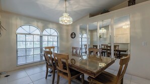 A dining area with a large wooden table, chairs, and a chandelier. - Lovely three-bedroom two-bathroom with pool and spa, and a short distance to Tigertail (Marco Island)