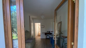Un pasillo con suelo de madera, una bicicleta y una zona de comedor con mesa y sillas.