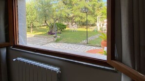 Una habitación con un ventanal que da a un jardín con árboles y césped.