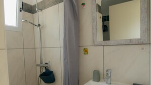 Een badkamer met een douche, een wastafel en een spiegel.