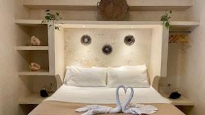 A neatly made bed with white linens and a heart-shaped towel arrangement. There are decorative wall mirrors and a woven basket above the bed. - Casa Caribe Tulum (Tulum)