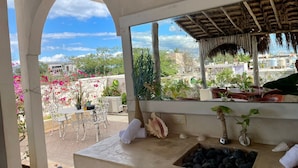 A covered outdoor seating area with a view of the city, a sink with black pebbles, and various plants and decorations. - Casa Caribe Tulum (Tulum)