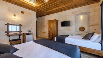 Una habitación con dos camas, techo de madera, televisor y un pequeño escritorio con teléfono.