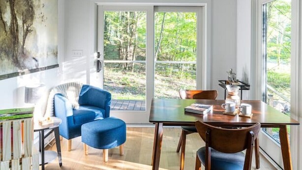 Un interior moderno con comedor, un sofá azul y un ventanal que ofrece vistas a zonas verdes.