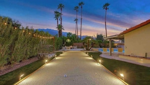 A croquet court with a pool and palm trees in the background. - Paramount Palm Springs: An Enchanting Hollywood (Palm Springs)