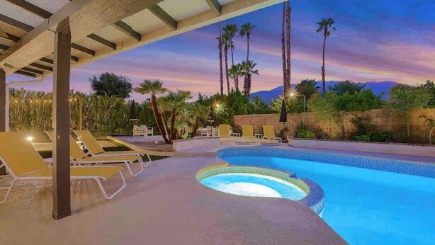 A swimming pool with lounge chairs and palm trees, surrounded by a landscaped area. - Paramount Palm Springs: An Enchanting Hollywood (Palm Springs)