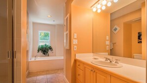 A modern bathroom with a bathtub, a sink, and a large mirror. - Banana Key (Key West)