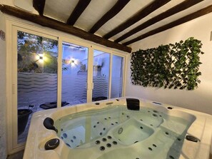 A hot tub in a room with a window and a wall-mounted plant.