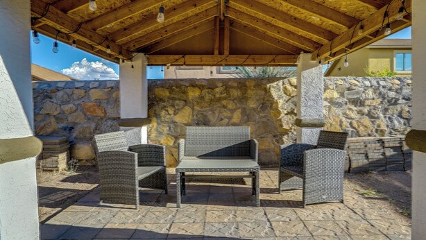 An outdoor patio with stone walls, a wooden ceiling, and wicker furniture. - Sunny El Paso Home w/ Private Yard! (El Paso)