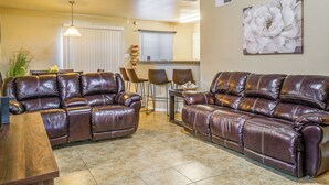 A living room with two brown leather sofas, a wooden coffee table, and a dining area with chairs and a table. - Sunny El Paso Home w/ Private Yard! (El Paso)