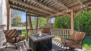 An outdoor patio with a fire pit table, two cushioned chairs, and a wooden pergola. - Charming Home With RV Parking, 30 Miles From Rmnp (Loveland)