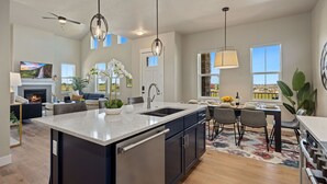 A modern kitchen with a central island, stainless steel appliances, and pendant lighting. - Elegant Home Near TPC Golf Course and Trails (Loveland)