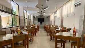 A spacious dining area with multiple tables and chairs, ceiling fans, and large windows. - Hotel San Francisco (Barranquilla)