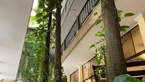 A multi-story building with balconies, surrounded by lush greenery and plants. - Hotel San Francisco (Barranquilla)