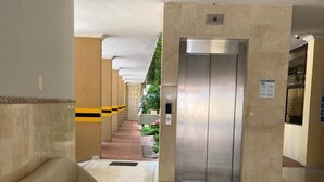 A hotel lobby with a sofa, a staircase, and an elevator. - Hotel San Francisco (Barranquilla)