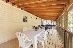 Un espace extérieur abrité, doté d’une terrasse en bois, d’une table avec des chaises et d’une rambarde.