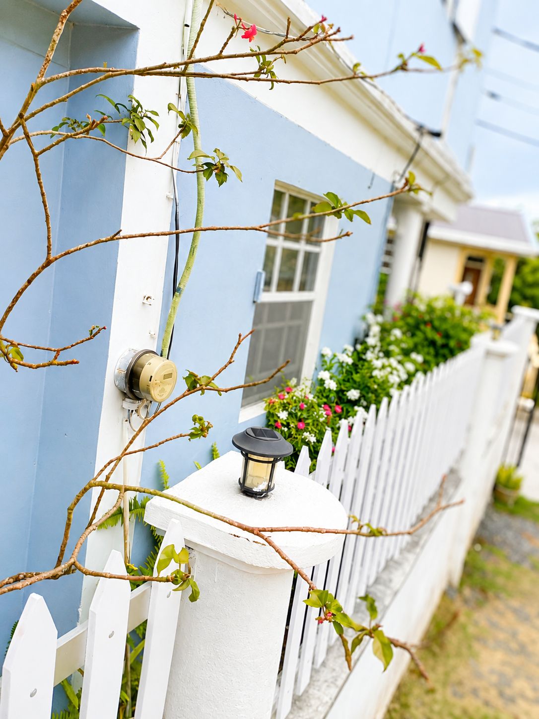 A house with a white picket fence, a blue exterior wall, and a small window.