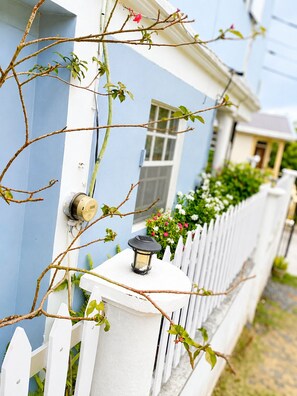 A house with a white picket fence, a blue exterior wall, and a small window. - NIZA’S PLACE—Cozy Mountainside Villa with Ocean view. (Paix Bouche)