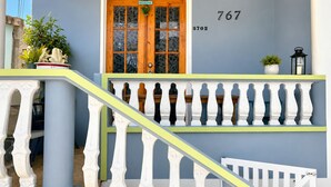 Una escalera con balaustradas blancas, una puerta de madera con un letrero de bienvenida y el número '767' en la pared.