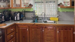 Una cocina con armarios de madera, un lavamanos y varios electrodomésticos.