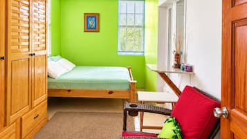 Ein Schlafzimmer mit Bett, Stuhl, Kleiderschrank, Deckenventilator und Fenster.